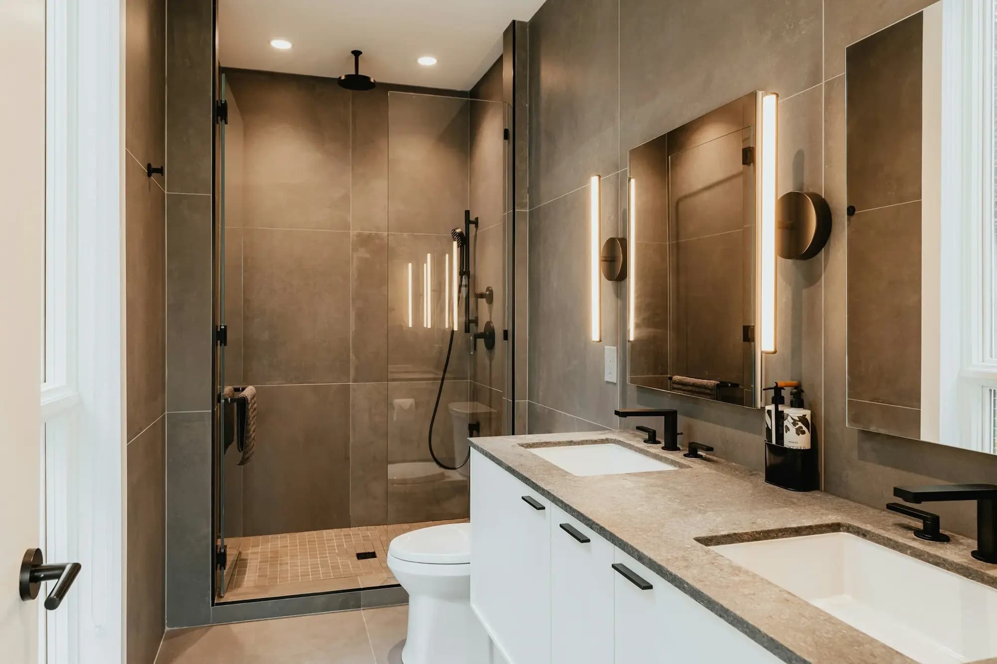 Ensuite with a walk-in shower in large-format tiles, a stone-topped vanity and backlit mirror